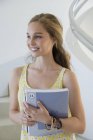 Happy female teenage student holding books on stairs — Stock Photo