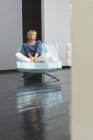Расслабленная зрелая женщина сидит на диване в квартире — стоковое фото