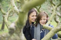 Женщина с дочерью-подростком смотрит на ветку деревьев в саду — стоковое фото