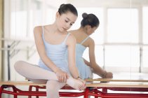 Маленькая балерина, растянувшаяся на зеркало в танцевальной студии — стоковое фото