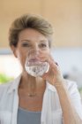 Primo piano della donna anziana che beve acqua dal vetro — Foto stock