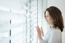 Thoughtful woman looking out of window in room — Stock Photo