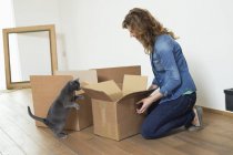 Frau sieht Katze in Wohnung an und lächelt — Stockfoto