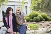 Романтическая пара, сидящая в саду и улыбающаяся — стоковое фото