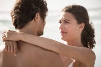 Primer plano de la joven mujer abrazando novio en la playa - foto de stock
