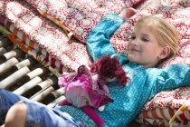 Porträt eines kleinen Mädchens, das mit Spielzeug in der Hängematte liegt — Stockfoto