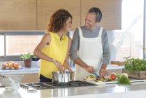 Happy couple preparing food in kitchen together — Stock Photo