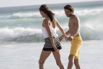 Счастливая молодая пара, гуляющая по пляжу — стоковое фото