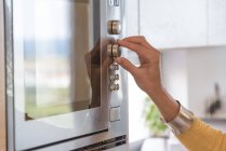 Close-up of female hand switching button of microwave — Stock Photo