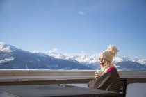 Жінка сидить чашкою ароматної кави на терасі з видом на гори, Кранс-Монтана, швейцарські Альпи, Швейцарія — стокове фото