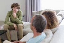 Smiling boy talking to parents while sitting on sofa in living room at home — Stock Photo