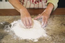 Primer plano de las manos femeninas mezclando harina en el mostrador de la cocina - foto de stock