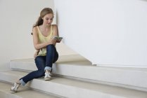 Adolescente sentada em passos e usando smartphone — Fotografia de Stock