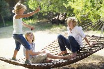 Smiling little siblings playing in hammock in summer garden — Stock Photo