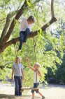 Lächelnde kleine Geschwister spielen auf Baumschaukel im Sommergarten — Stockfoto