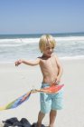Joyeux garçon tenant cerf-volant sur la plage de sable — Photo de stock