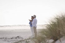 Happy senior couple talking on sandy beach — Stock Photo