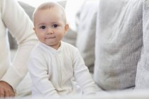 Happy baby girl sitting on couch at home — Stock Photo
