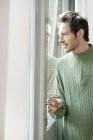 Чоловік в пуловері дивиться через скло дверей — стокове фото