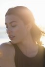 Чуттєва молода жінка позує на пляжі на сонячному світлі — стокове фото