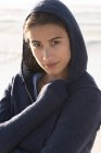 Close-up of young charming woman in hoodie on beach — Stock Photo