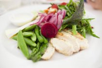 Primer plano de ensalada verde con espárragos, frijoles, rodajas de cebolla y otras verduras - foto de stock