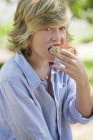 Garçon aux cheveux blonds manger sandwich à l'extérieur — Photo de stock