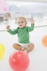 Niedliche Baby-Junge spielt mit Luftballons auf dem Boden — Stockfoto