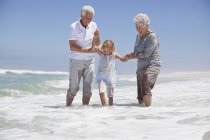 Menina se divertindo na praia do mar com os avós — Fotografia de Stock