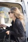 Elegante donna d'affari in occhiali da sole mettere i bagagli in auto — Foto stock