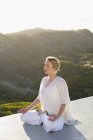Расслабленная женщина в белом наряде медитирует на природе — стоковое фото