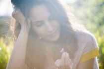 Мечтательная женщина в солнечной природе держа маленький цветок ромашки — стоковое фото