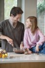 Mann rührt in Schüssel mit Tochter in Küche — Stockfoto