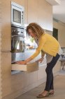 Donna in abito casual apertura cassetto in cucina — Foto stock