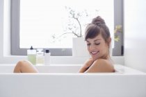 Усміхнена молода жінка розслабляється у ванній — стокове фото