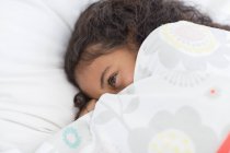 Close-up of cute little girl lying on bed — Stock Photo