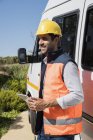 Усміхнений чоловічий інженер з цифровим планшетом, що стоїть на фургоні — стокове фото