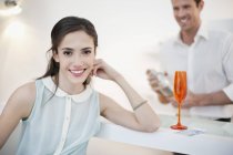 Женщина улыбается с мужем, трясущим коктейль на заднем плане — стоковое фото