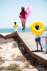 Frau läuft mit ihren Kindern auf einer Strandpromenade — Stockfoto