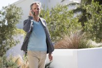 Взрослый мужчина разговаривает по мобильному телефону в саду — стоковое фото