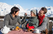 Casal e filha comendo na varanda na estância de esqui — Fotografia de Stock