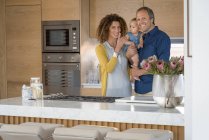 Glückliches Paar steht mit kleiner Tochter in Küche — Stockfoto