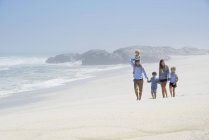 Familia feliz con niños caminando en la playa - foto de stock