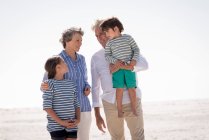Felice nonni con nipoti godendo sulla spiaggia — Foto stock