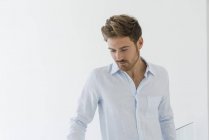 Портрет элегантного молодого человека в белой рубашке, смотрящего вниз — стоковое фото