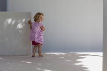 Rear view of cute baby girl standing against a wall outdoors — Stock Photo