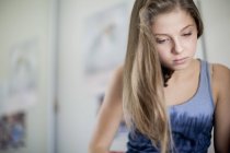 Thoughtful teenage girl sitting on blurred background — Stock Photo