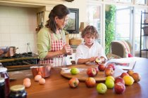 Grandmother and little boy peeling an apple at home — Stock Photo