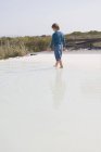 Rear view of little boy walking in infinity pool — Stock Photo
