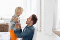 Young man playing with his son at home — Stock Photo